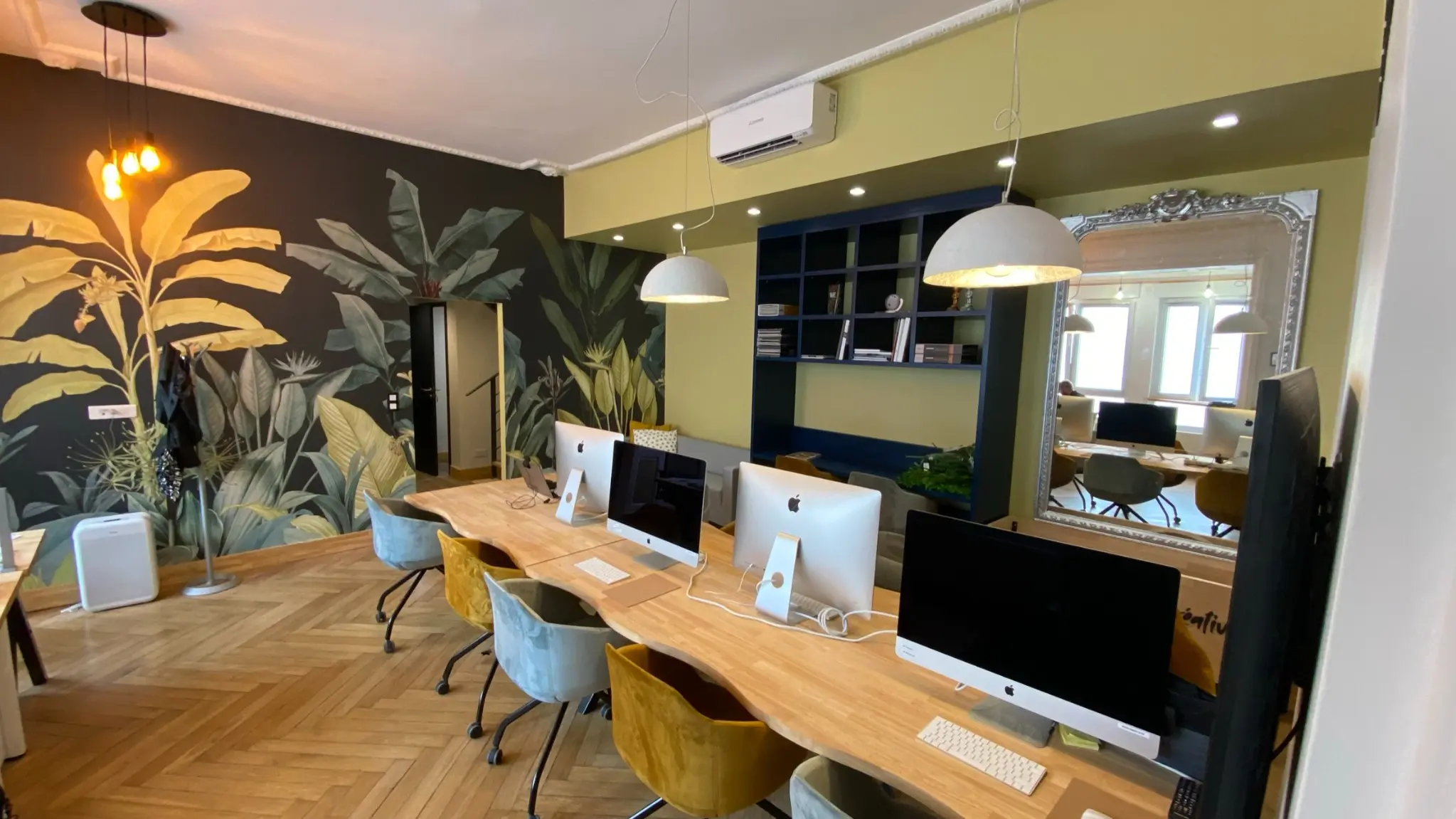 Agence créative avec fresque végétale et postes de travail